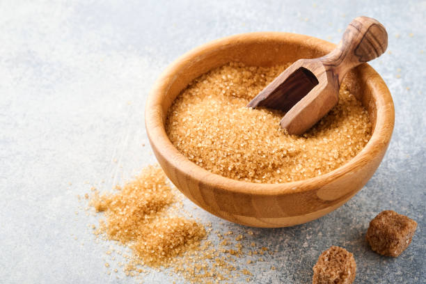 Cane sugar cube in bamboo bowl on gray table concrete background. Top view.